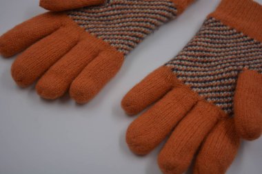 Sıcak, yumuşak, kışlık eşyalar ve ev eşyaları. Güzel turuncu, gri, yalıtılmış, örgü eldivenler beyaz plastik bir arka planda bulunur..