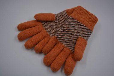 Sıcak, yumuşak, kışlık eşyalar ve ev eşyaları. Güzel turuncu, gri, yalıtılmış, örgü eldivenler beyaz plastik bir arka planda bulunur..