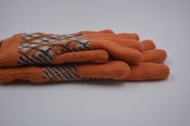 Sıcak, yumuşak, kışlık eşyalar ve ev eşyaları. Güzel turuncu, gri, yalıtılmış, örgü eldivenler beyaz plastik bir arka planda bulunur..