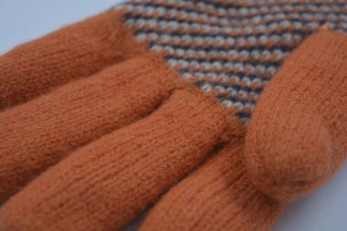 Sıcak, yumuşak, kışlık eşyalar ve ev eşyaları. Güzel turuncu, gri, yalıtılmış, örgü eldivenler beyaz plastik bir arka planda bulunur..