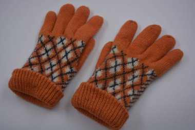 Sıcak, yumuşak, kışlık eşyalar ve ev eşyaları. Güzel turuncu, gri, yalıtılmış, örgü eldivenler beyaz plastik bir arka planda bulunur..