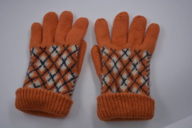 Sıcak, yumuşak, kışlık eşyalar ve ev eşyaları. Güzel turuncu, gri, yalıtılmış, örgü eldivenler beyaz plastik bir arka planda bulunur..