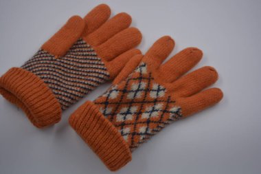 Sıcak, yumuşak, kışlık eşyalar ve ev eşyaları. Güzel turuncu, gri, yalıtılmış, örgü eldivenler beyaz plastik bir arka planda bulunur..