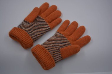 Sıcak, yumuşak, kışlık eşyalar ve ev eşyaları. Güzel turuncu, gri, yalıtılmış, örgü eldivenler beyaz plastik bir arka planda bulunur..