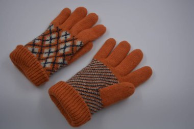 Sıcak, yumuşak, kışlık eşyalar ve ev eşyaları. Güzel turuncu, gri, yalıtılmış, örgü eldivenler beyaz plastik bir arka planda bulunur..