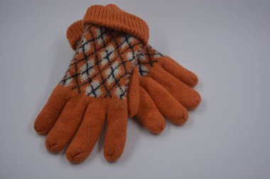 Sıcak, yumuşak, kışlık eşyalar ve ev eşyaları. Güzel turuncu, gri, yalıtılmış, örgü eldivenler beyaz plastik bir arka planda bulunur..