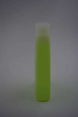 Eşyalar, ev kimyasalları, kozmetik ürünler, duş jeli, şampuan. Şeffaf kapaklı mat beyaz şişe parlak, zehirli yeşil, sarı sıvı jel.