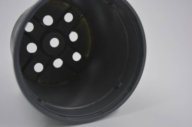 Eşyalar, günlük hayatta sürekli kullanılan nesneler. İnce gri plastik saksı, konteynır beyaz plastik arka plan üzerine yerleştirilmiş..