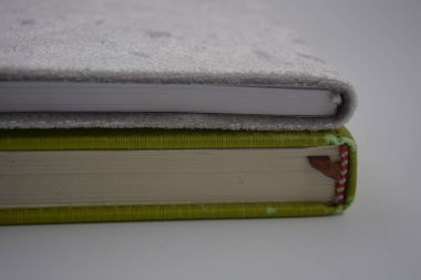 Eşyalar ve objeler, eğitim. Güzel kitaplar, parlak yeşil renkli bir defter, beyaz, boş çarşaflı, beyaz bir kağıt beyaz plastik arka planda yer alır..