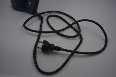 Bilgisayar, teknik şeyler, günlük hayatta kullanılan cihazlar. Siyah, kalın ve siyah metal prizli bir kablo beyaz plastik arka planda yer alır..