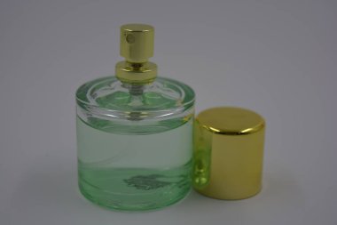 Nesneler, eşyalar, kozmetik ürünler ve parfümler. Beyaz plastik arka planda, üzerinde kadın parfümleri ve altın plastikten bir şapka bulunan güzel bir cam şişe..