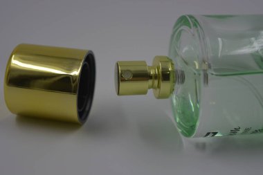 Nesneler, eşyalar, kozmetik ürünler ve parfümler. Beyaz plastik arka planda, üzerinde kadın parfümleri ve altın plastikten bir şapka bulunan güzel bir cam şişe..