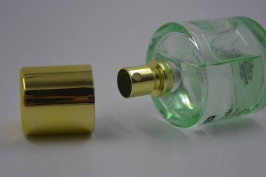 Nesneler, eşyalar, kozmetik ürünler ve parfümler. Beyaz plastik arka planda, üzerinde kadın parfümleri ve altın plastikten bir şapka bulunan güzel bir cam şişe..