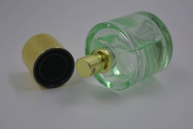 Nesneler, eşyalar, kozmetik ürünler ve parfümler. Beyaz plastik arka planda, üzerinde kadın parfümleri ve altın plastikten bir şapka bulunan güzel bir cam şişe..