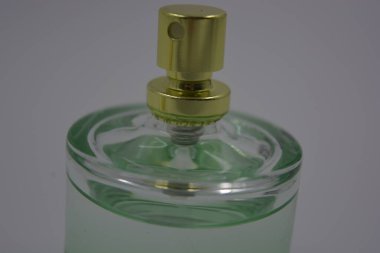 Nesneler, eşyalar, kozmetik ürünler ve parfümler. Beyaz plastik arka planda, üzerinde kadın parfümleri ve altın plastikten bir şapka bulunan güzel bir cam şişe..