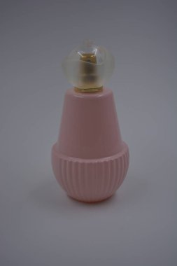 Nesneler, eşyalar, kozmetik ürünler ve parfümler. Beyaz plastik arka planda, üzerinde kadın parfümleri, altın sprey ve beyaz bir plastik şapka bulunan güzel, pembe bir şişe bulunur..