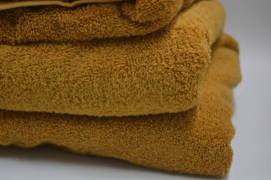 Günlük hayatta güzel ve sıradan şeyler. Güzel, pofuduk, turuncu, kırmızı pamuklu, terry havluları beyaz plastik arka planda yer alır..