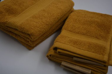 Günlük hayatta güzel ve sıradan şeyler. Güzel, pofuduk, turuncu, kırmızı pamuklu, terry havluları beyaz plastik arka planda yer alır..