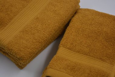 Günlük hayatta güzel ve sıradan şeyler. Güzel, pofuduk, turuncu, kırmızı pamuklu, terry havluları beyaz plastik arka planda yer alır..