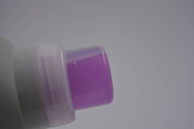 Eşyalar, günlük hayatta kullanılan nesneler. Mor temizlik sıvısıyla dolu büyük plastik bir şişe ve beyaz plastik arka plan üzerine temiz bir plastik kapak yerleştirilir..