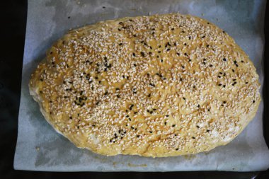 Evde yapılan taze, lezzetli beyaz ekmek. Beyaz ve siyah susam tohumlu iki somun ekmek beyaz parşömen kağıdına konur..