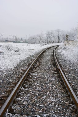 Winter landscape, wide metal roads with grey gravel covered with a thin layer of white snow. Winter, snowy landscape, bright white snow lies on the railway line.