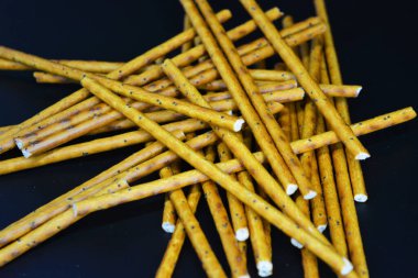 Fast food, gıda ürünleri. Polietilen ambalajda paketlenmiş ve siyah plastik arka planda bulunan uzun buğday kamışları.