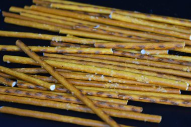 Fast food, gıda ürünleri. Polietilen ambalajda paketlenmiş ve siyah plastik arka planda bulunan uzun buğday kamışları.