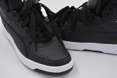 Güzel, genç spor ayakkabıları, beyaz sert tabanlı siyah çizmeler beyaz plastiğin üzerinde.. İzolasyonlu, sentetik kürklü, güzel pamuklu siyah bağcıklı deri botlar..