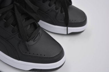 Güzel, genç spor ayakkabıları, beyaz sert tabanlı siyah çizmeler beyaz plastiğin üzerinde.. İzolasyonlu, sentetik kürklü, güzel pamuklu siyah bağcıklı deri botlar..