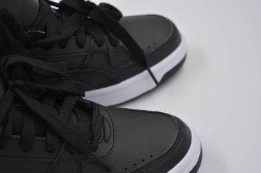 Güzel, genç spor ayakkabıları, beyaz sert tabanlı siyah çizmeler beyaz plastiğin üzerinde.. İzolasyonlu, sentetik kürklü, güzel pamuklu siyah bağcıklı deri botlar..