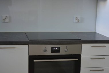 Mutfak gereçleri, gri mutfak tezgahı, beyaz dolaplar, beyaz Avrupa tıkaçlı gri elektrikli fırın olan tipik bir Finlandiya mutfağı..