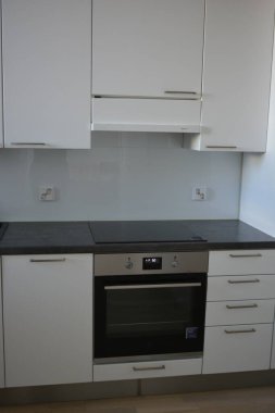 Mutfak gereçleri, gri mutfak tezgahı, beyaz dolaplar, beyaz Avrupa tıkaçlı gri elektrikli fırın olan tipik bir Finlandiya mutfağı..