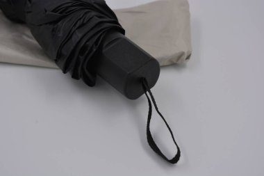 Yeni, güzel bej, altın, beyaz, siyah saplı, açık renk şemsiye, su ve yağmurdan siyah astarlı beyaz plastik arka planda yer almaktadır..