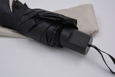 Yeni, güzel bej, altın, beyaz, siyah saplı, açık renk şemsiye, su ve yağmurdan siyah astarlı beyaz plastik arka planda yer almaktadır..