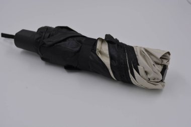 Yeni, güzel bej, altın, beyaz, siyah saplı, açık renk şemsiye, su ve yağmurdan siyah astarlı beyaz plastik arka planda yer almaktadır..