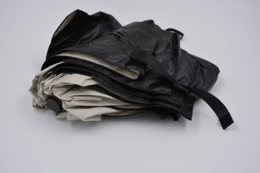 Yeni, güzel bej, altın, beyaz, siyah saplı, açık renk şemsiye, su ve yağmurdan siyah astarlı beyaz plastik arka planda yer almaktadır..