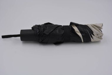 Yeni, güzel bej, altın, beyaz, siyah saplı, açık renk şemsiye, su ve yağmurdan siyah astarlı beyaz plastik arka planda yer almaktadır..
