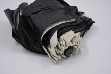 Yeni, güzel bej, altın, beyaz, siyah saplı, açık renk şemsiye, su ve yağmurdan siyah astarlı beyaz plastik arka planda yer almaktadır..