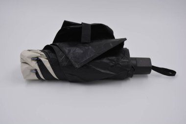 Yeni, güzel bej, altın, beyaz, siyah saplı, açık renk şemsiye, su ve yağmurdan siyah astarlı beyaz plastik arka planda yer almaktadır..