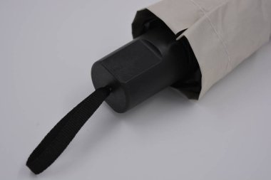 Yeni, güzel bej, altın, beyaz, siyah saplı, açık renk şemsiye, su ve yağmurdan siyah astarlı beyaz plastik arka planda yer almaktadır..