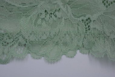 Çiçek tomurcuklarından, çiçek açan güllerden, şakayıklardan yeşil zeytin güzel dantel. Alışılmadık bir kumaş, doğal pamuktan yapılmış açık yeşil kumaşa işlenmiş parıltılı dantel..