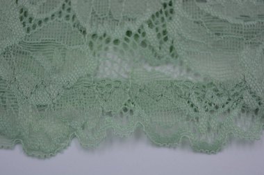 Çiçek tomurcuklarından, çiçek açan güllerden, şakayıklardan yeşil zeytin güzel dantel. Alışılmadık bir kumaş, doğal pamuktan yapılmış açık yeşil kumaşa işlenmiş parıltılı dantel..