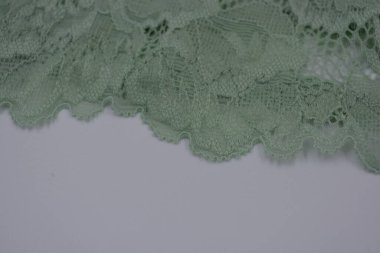 Çiçek tomurcuklarından, çiçek açan güllerden, şakayıklardan yeşil zeytin güzel dantel. Alışılmadık bir kumaş, doğal pamuktan yapılmış açık yeşil kumaşa işlenmiş parıltılı dantel..