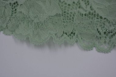 Çiçek tomurcuklarından, çiçek açan güllerden, şakayıklardan yeşil zeytin güzel dantel. Alışılmadık bir kumaş, doğal pamuktan yapılmış açık yeşil kumaşa işlenmiş parıltılı dantel..