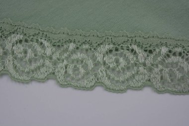 Çiçek tomurcuklarından, çiçek açan güllerden, şakayıklardan yeşil zeytin güzel dantel. Alışılmadık bir kumaş, doğal pamuktan yapılmış açık yeşil kumaşa işlenmiş parıltılı dantel..
