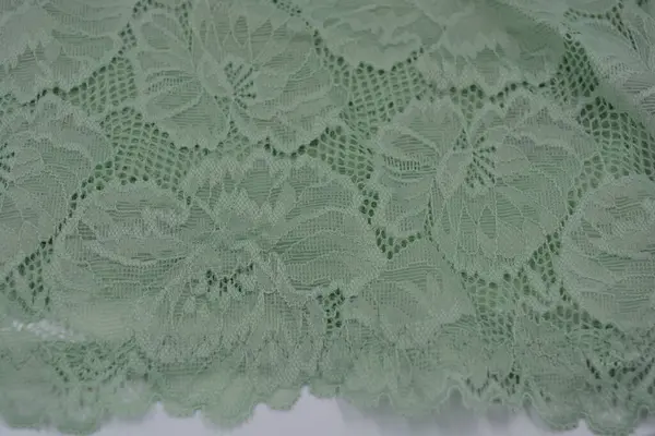 Çiçek tomurcuklarından, çiçek açan güllerden, şakayıklardan yeşil zeytin güzel dantel. Alışılmadık bir kumaş, doğal pamuktan yapılmış açık yeşil kumaşa işlenmiş parıltılı dantel..
