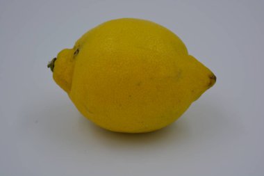 Ürünler, sağlıklı ve sağlıklı yiyecekler, taze meyveler. Olgun sulu sarı limon beyaz plastik arka planda yer alır..