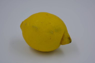 Ürünler, sağlıklı ve sağlıklı yiyecekler, taze meyveler. Olgun sulu sarı limon beyaz plastik arka planda yer alır..