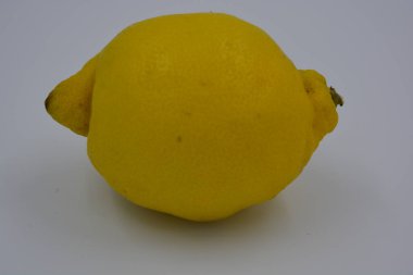 Ürünler, sağlıklı ve sağlıklı yiyecekler, taze meyveler. Olgun sulu sarı limon beyaz plastik arka planda yer alır..